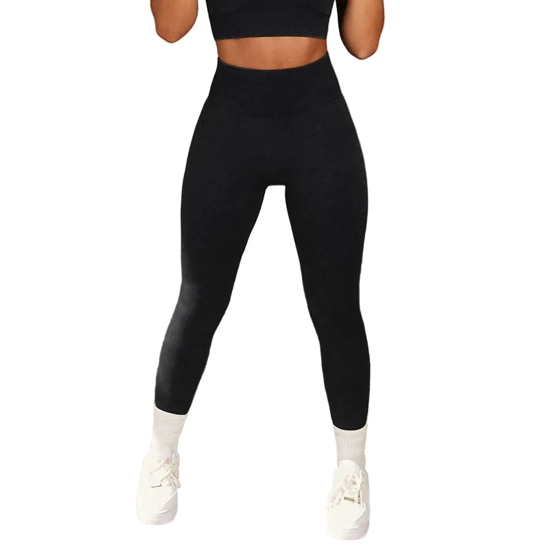 Person wearing black leggings and white sneakers against a concrete wall.