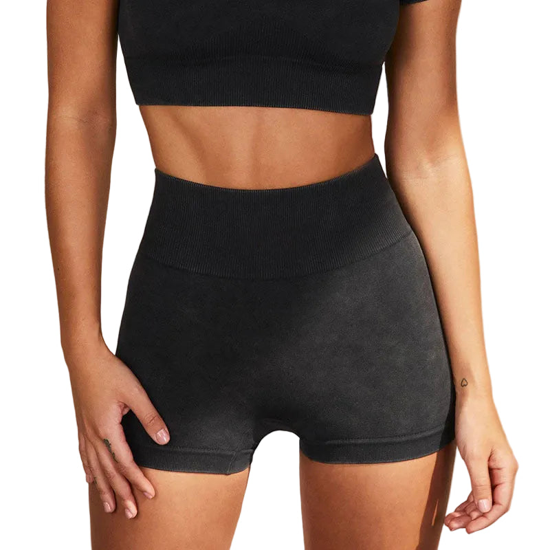 Person wearing black high-waisted shorts and a black crop top against a beige background