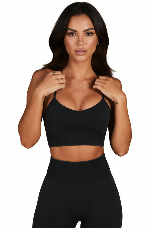 Woman wearing a black sports bra and leggings against a neutral background