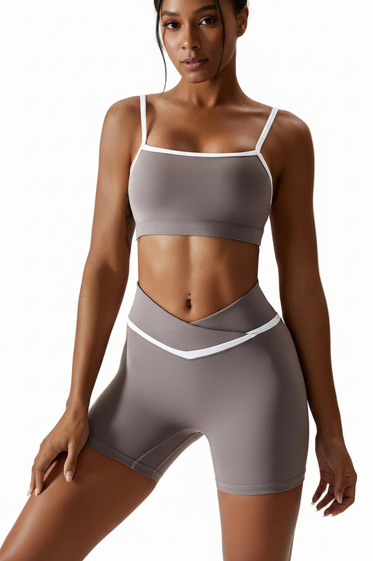 Woman wearing a gray sports bra and shorts set on a light gray background